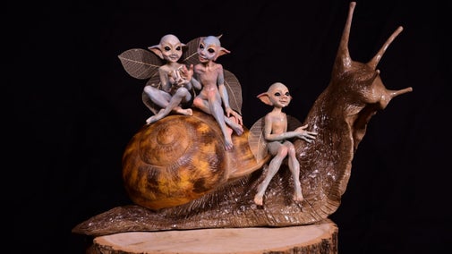 Orange sculptures of three mischievous looking Cornish pixies